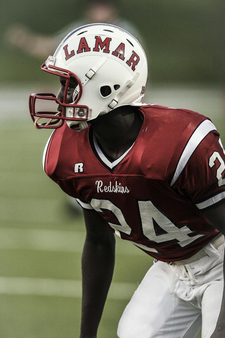 A determined football player in red uniform ready for a game on the field.